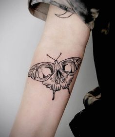 a black and white photo of a moth tattoo on the left inner arm, with an eyeball in the middle