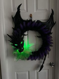 a door decorated with a dragon head and green light in the dark, on top of a white door