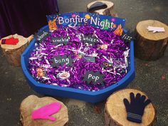 purple shredded paper in a blue bowl with wooden stumps and hand mitts next to it