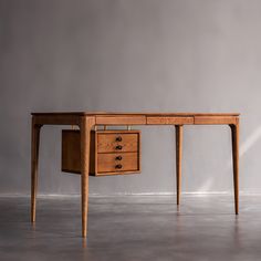 a wooden desk with two drawers sitting on top of concrete floor next to a wall