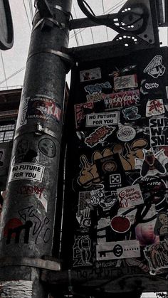 a street sign covered in lots of stickers on it's side next to a pole