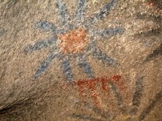 an image of some kind of rock with flowers on it's face and other symbols painted on the rocks