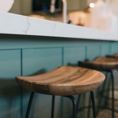 three wooden stools sitting next to each other in front of a kitchen counter top