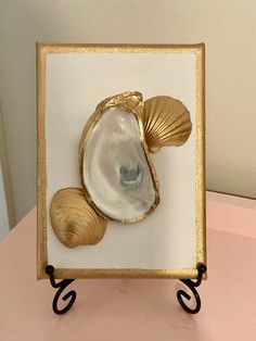 there is a shell and two seashells in a frame on top of a table