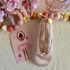 a pair of pink ballet shoes sitting on top of a table next to some flowers