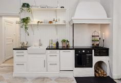 two screens show the interior and exterior of a kitchen with white cabinets, black countertops, and wood floors