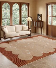 a living room filled with furniture and windows next to a large rug on the floor