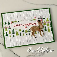 a merry christmas card with a deer and trees on the front, in green and white