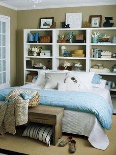 a bed sitting in a bedroom next to a white book shelf filled with books and other items