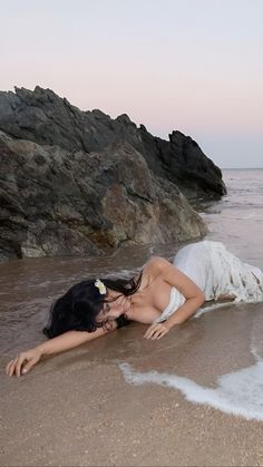 a woman laying on top of a sandy beach next to the ocean