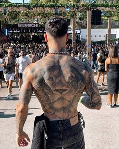 a man with a lion tattoo on his back in front of a large group of people