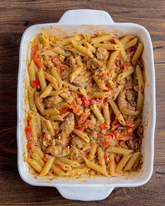 a casserole dish filled with pasta, meat and sauce on a wooden table