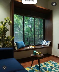 a living room filled with furniture next to a window covered in blue and yellow pillows