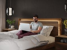 a man sitting on his bed using a laptop