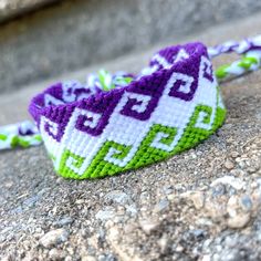 a purple and green beaded headband sitting on top of a stone wall next to some rocks