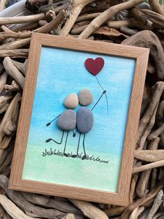 two rocks in the shape of an ostrich holding a heart shaped balloon on top of some driftwood