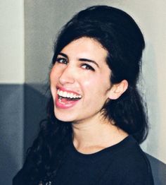 a woman with long black hair smiling at the camera