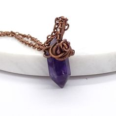 Delicate copper necklace with an unusual amethyst in the form of an icicle in a beautiful purple color. Amethyst is considered a stone that brings peace, a sense of security and harmony. The necklace in the form of an unusual talisman looks great both in boho-inspired outfits and in casual style, giving it an artistic touch. The stone is wrapped in copper and oxidized (i.e. darkened). The pendant is approx. 28mm high The necklace is suspended on a long chain made of anti-allergic metals, approx. Handmade Purple Necklace With Copper Wire, Handmade Purple Copper Wire Necklace, Mystical Hand Wrapped Pendant Necklace, Hand Forged Amethyst Pendant Necklace, Purple Gemstone Copper Jewelry, Electroformed Amethyst Crystal Necklace As Gift, Handmade Purple Copper Jewelry, Hand Forged Amethyst Bronze Jewelry, Hand Forged Purple Necklace For Gift