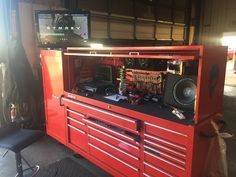 a large red tool cabinet with many tools on it's sides and two speakers