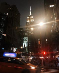 a city street filled with lots of traffic and tall buildings in the background at night