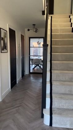 an empty hallway with stairs leading up to the door and another room in the background