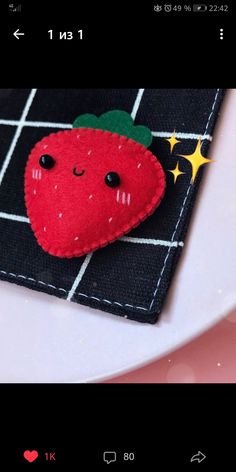 a red strawberry brooch sitting on top of a black cloth