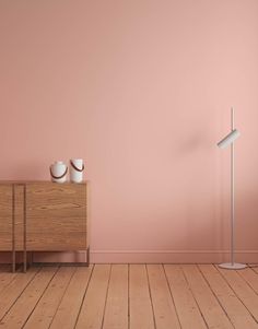 an empty room with pink walls and two white vases on the dresser next to it