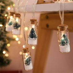 mason jar filled with snow and trees hanging from strings