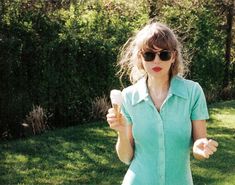 a woman holding an ice cream cone in her right hand and wearing sunglasses on the other