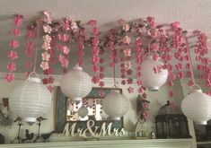 some paper lanterns hanging from the ceiling with pink flowers on them and mr and mrs sign