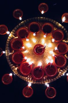 many lit candles in a glass bowl on top of a black surface with white lights