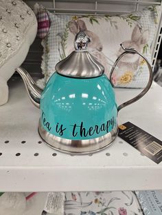 a tea pot with the words tea is therapy painted on it sitting on a shelf