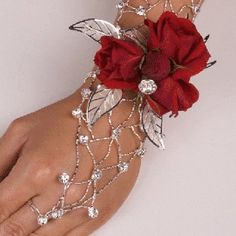 a woman's hand wearing a red flower and chain bracelet with jewels on it