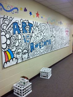 some crates are sitting on the floor in front of a wall with art written on it