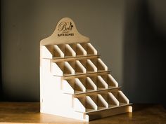 a wooden display case with six rows of folded papers on top of it, sitting on a table