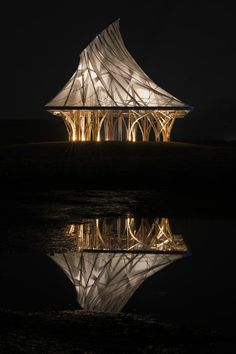 a building that is lit up at night with its lights on and reflecting in the water