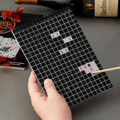 a person is holding a stick and playing with some dominos on a table next to wine bottles