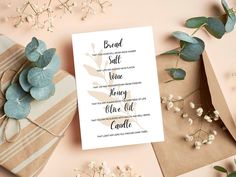 the wedding stationery is laid out on top of some wrapping paper, with flowers and greenery