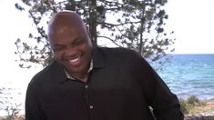 a man smiles as he stands in front of the ocean