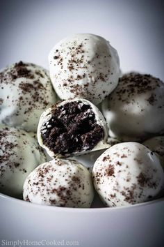 a white bowl filled with lots of chocolate covered doughnuts on top of each other