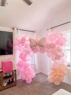 a room filled with balloons and bows on the ceiling next to a flat screen tv