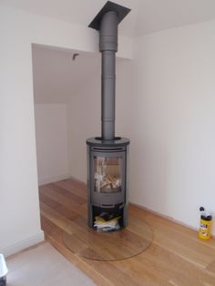 a wood burning stove sitting on top of a hard wood floor next to a white wall