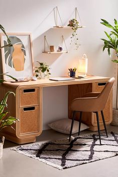 a white desk with a laptop on top of it next to a plant and other items