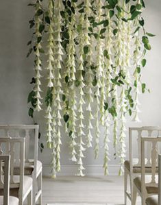 white flowers hanging from the ceiling in a room with two chairs and a table next to it