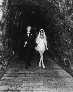 a bride and groom walking through a tunnel