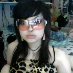 a woman wearing glasses and leopard print dress with her nose ring in front of her face