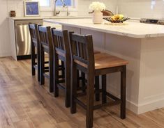 a kitchen island with four chairs and a sink in it, next to an oven