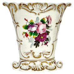 a white vase with flowers painted on the side and gold trimmings around it