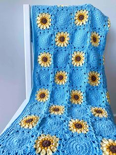 a blue crocheted blanket with sunflowers on it