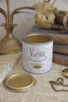 a can of vintage paint sitting on top of an open book next to some books